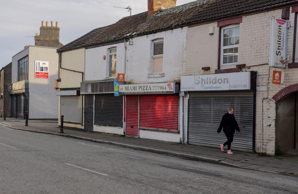 Shildon Town in Co Durham with closed shops and a woman walking by.