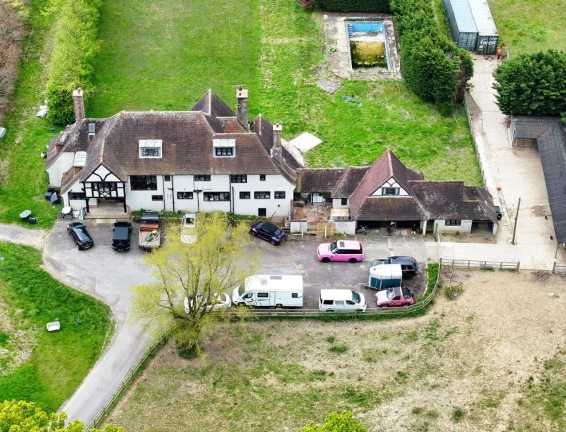 Aerial view of Katie Price's house, featuring multiple vehicles parked outside, surrounding grounds, and an empty swimming pool.