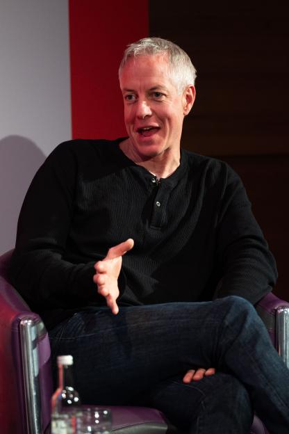 Production designer Mathieu Weekes talking while gesturing with his right hand.