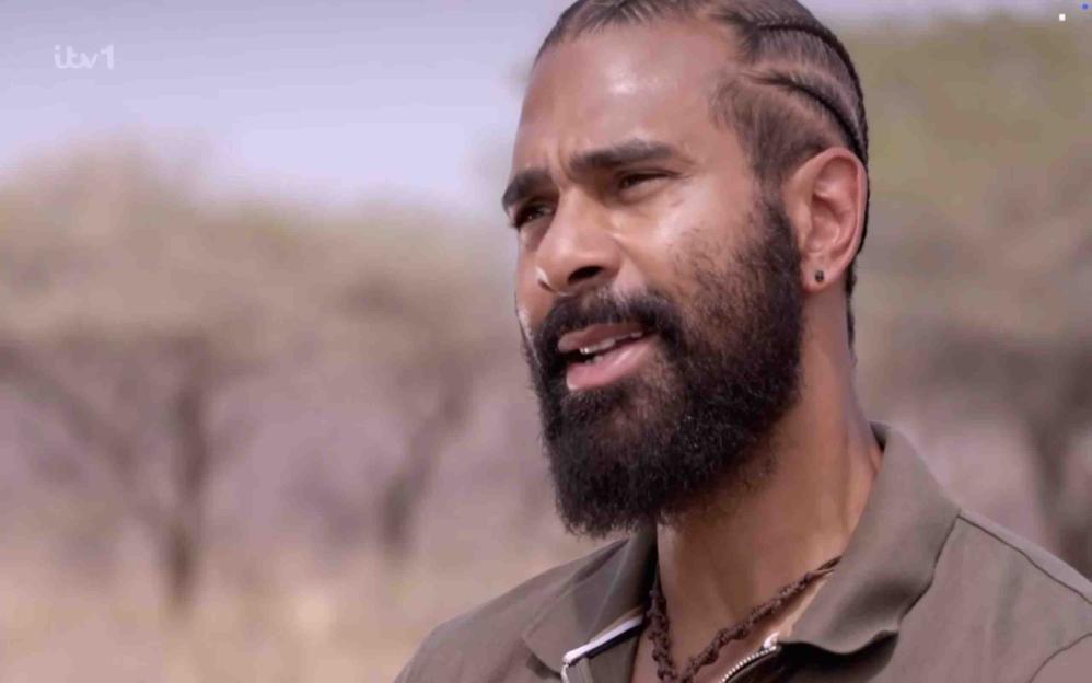 David Haye from "I'm A Celebrity... Get Me Out Of Here! South Africa" with braided hair, a beard, and a brown shirt.