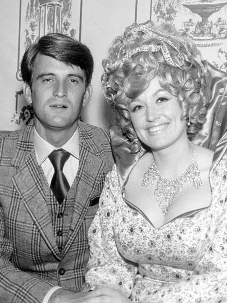 Dolly Parton and her husband Carl Dean, a man in a suit and tie, and a woman with an elaborate hairstyle and necklace.