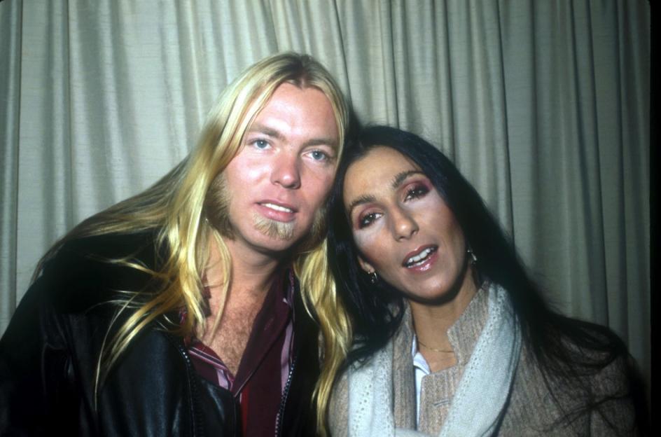 Cher with her arm around Gregg Allman, both looking forward.
