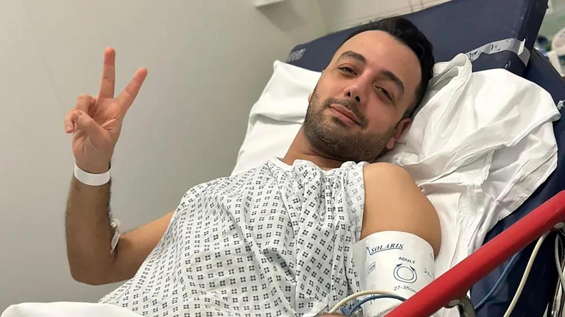 Pouria Zeraati in hospital, giving a peace sign.