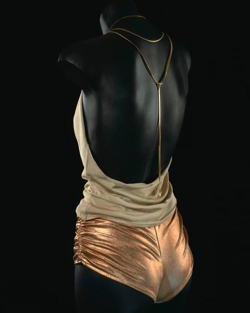 Kylie Minogue's gold hot pants and a beige top with a gold necklace, displayed on a mannequin.