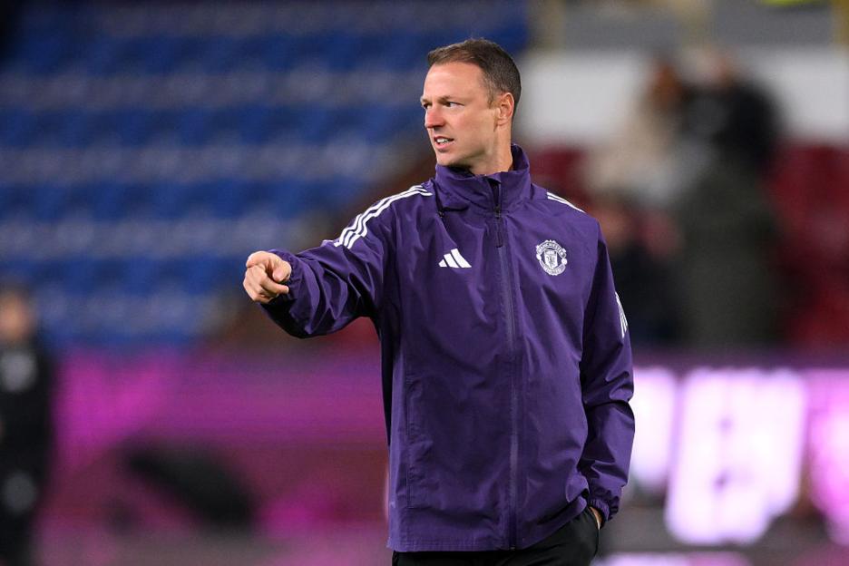 Jonny Evans, in a purple jacket, points his finger while looking left.
