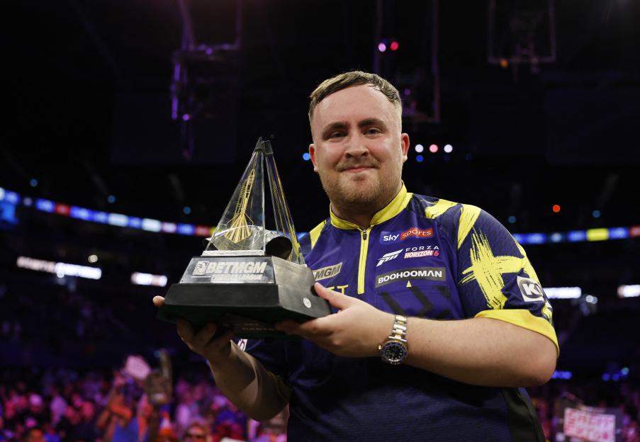 Luke Littler holding the Premier League Darts trophy.