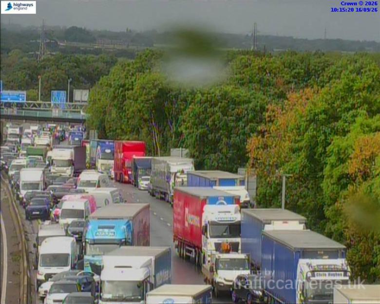 Heavy traffic congestion on a multi-lane highway, with many cars and semi-trucks visible.