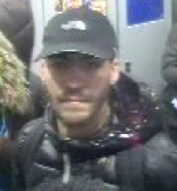 A man wearing a black baseball cap and a dark puffer jacket.