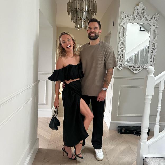 Ollie Piotrowski with his fiancée, Hollyoaks actress Jorgie Porter, smiling in a hallway.