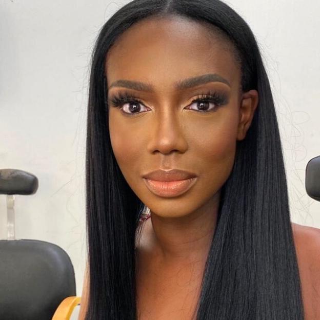 A woman with long black hair, brown eyes, and neutral makeup.