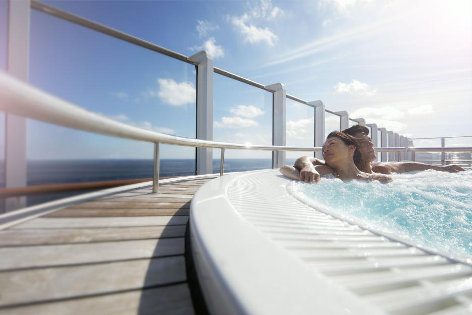 A couple relaxing in a hot tub on a cruise ship deck.