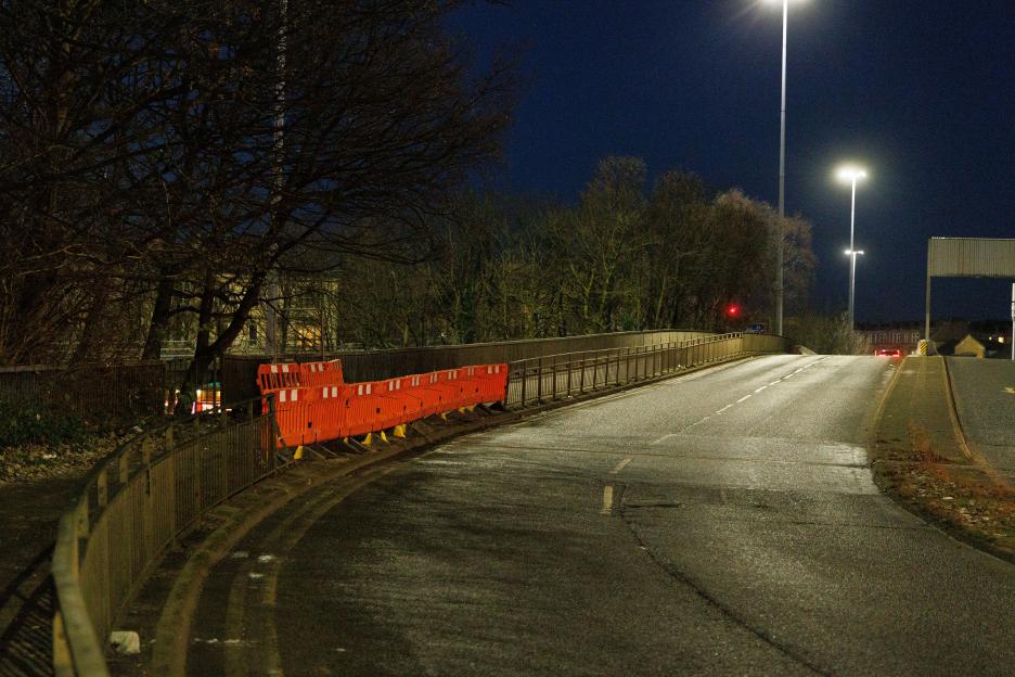 Street at night with orange barriers along the side of the road.