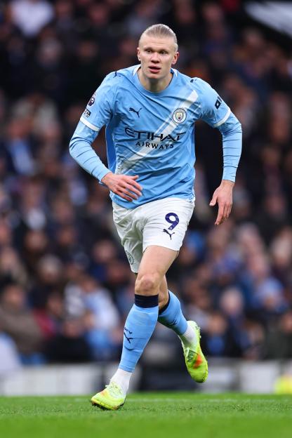 Manchester City player Erling Haaland in light blue uniform with the number 9, on a soccer field.