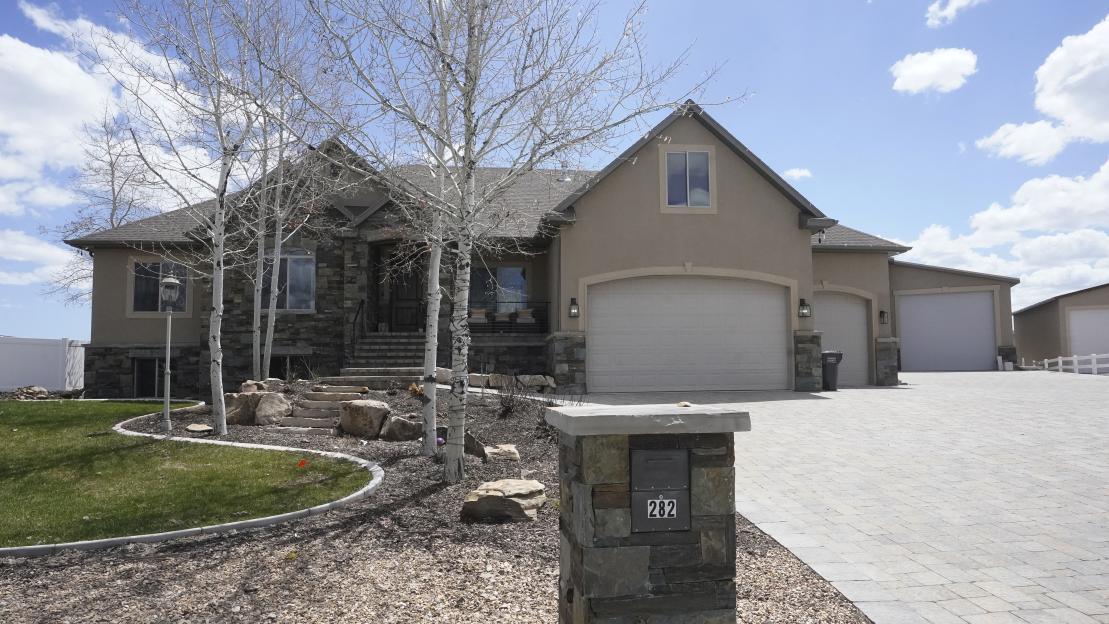 A house with a large garage and two white trees in front, with the address 282.