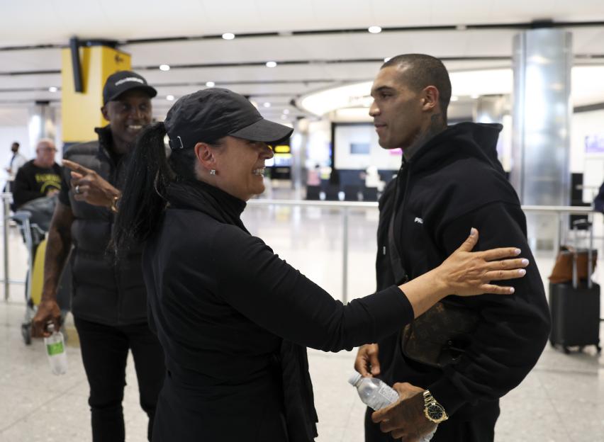 a woman in a black hat is hugging a man in a black hoodie