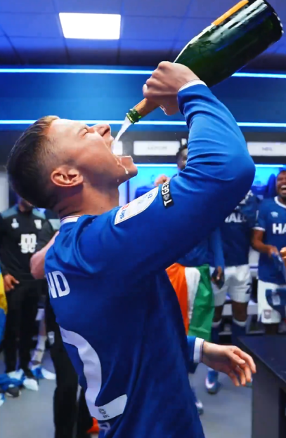 Soccer player drinking champagne from the bottle.