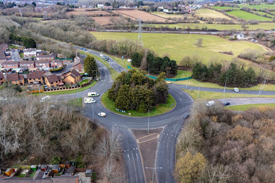 Aerial view of the scene of a fatal road traffic accident in St Mellons, Cardiff, showing multiple emergency vehicles around a roundabout and surrounding residential and rural areas.