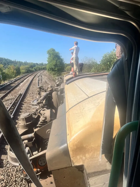 People on top of a derailed train car.