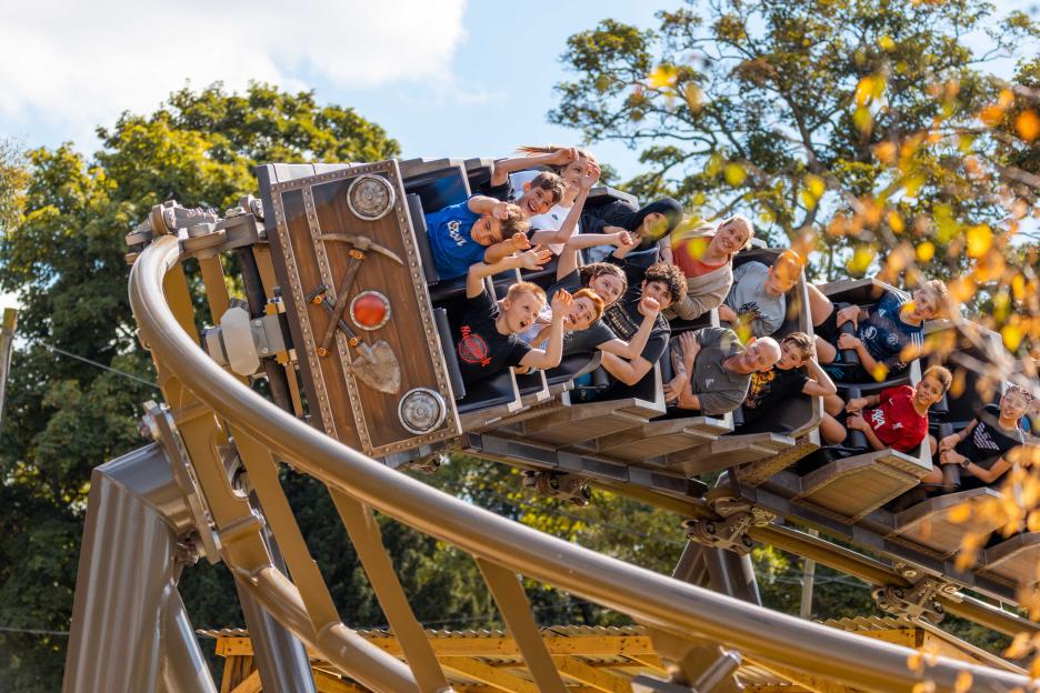 People riding a roller coaster designed to look like a gold rush mining cart.