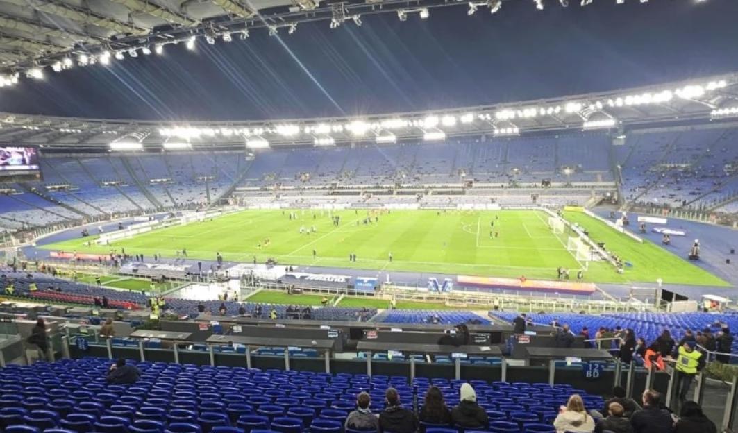 Soccer stadium with a few people in the stands and players on the field.