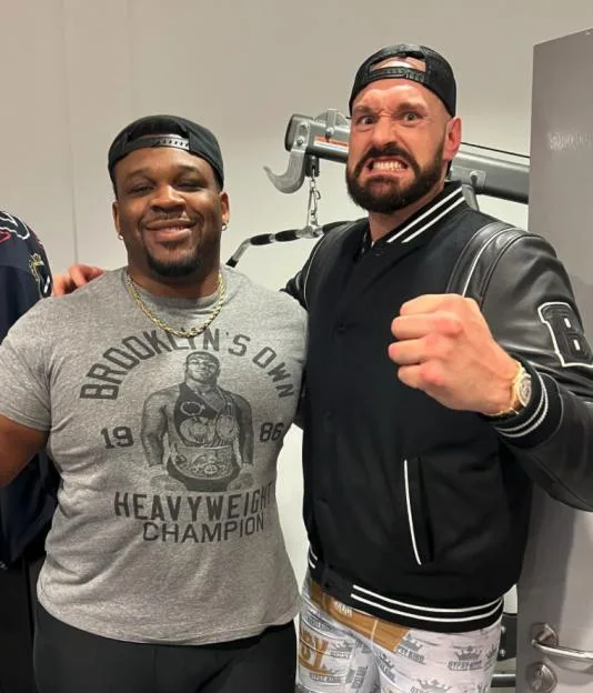 Jarrell Miller and Tyson Fury smiling together in a gym.