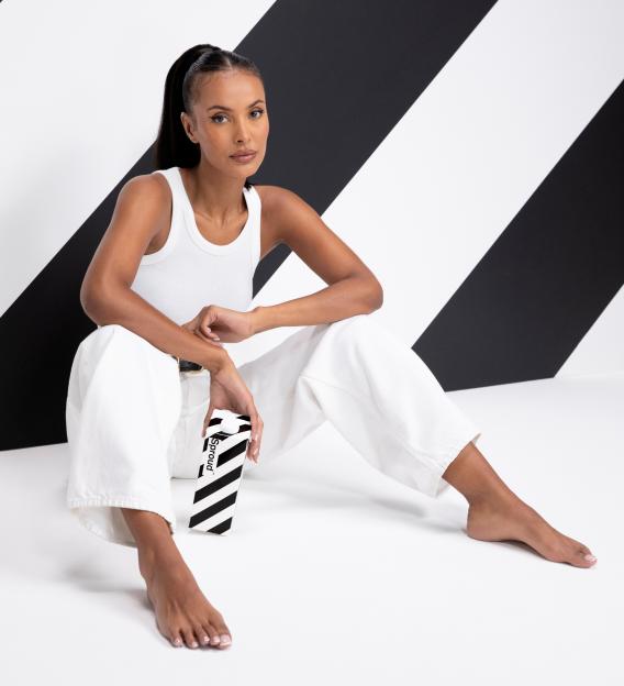 Maya Jama sits cross-legged on the floor, holding a carton of Sproud plant milk.