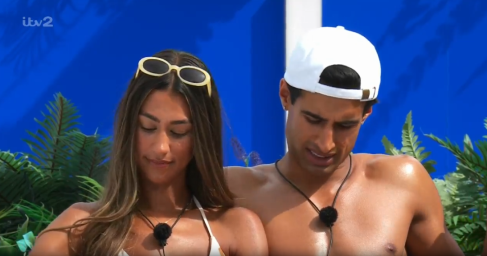 A man in a white hat and a woman in sunglasses looking down.