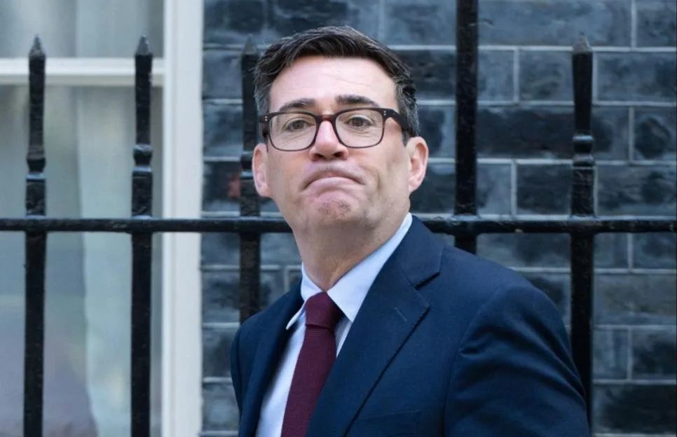 Prime Minister Andy Burnham leaves 10 Downing Street carrying a red folder.