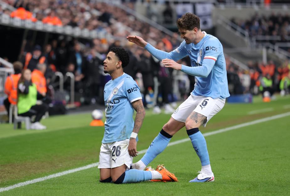 Savinho celebrates with John Stones after scoring Manchester City's first goal.