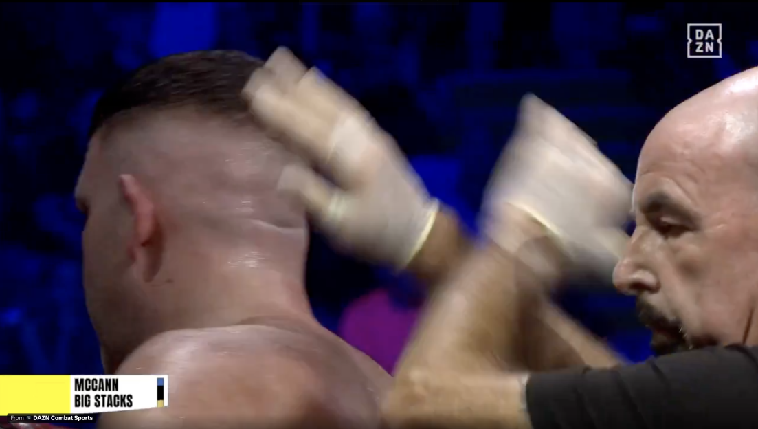Man in white gloves wiping sweat from a boxer's head.