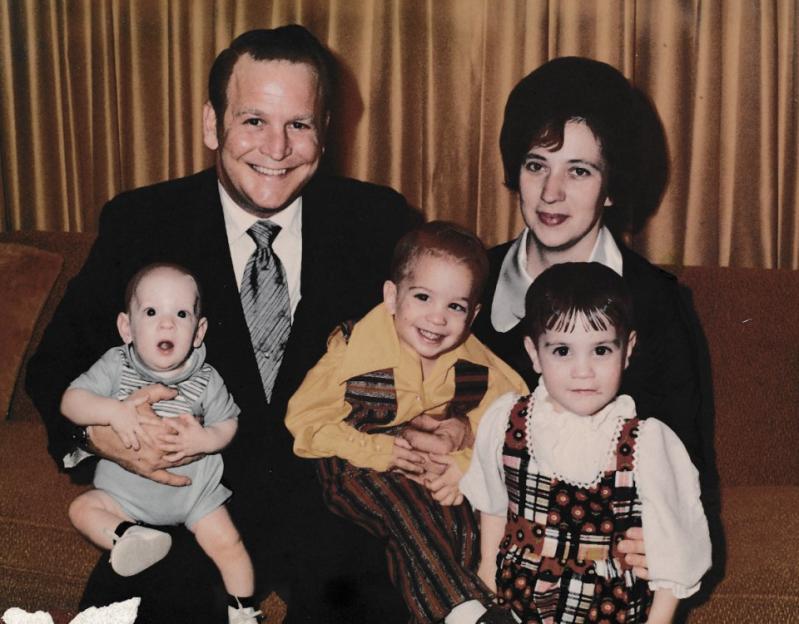 Family portrait of a smiling father, mother, and three young children.