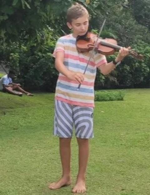 Eddie Jarman playing a violin outdoors while barefoot.