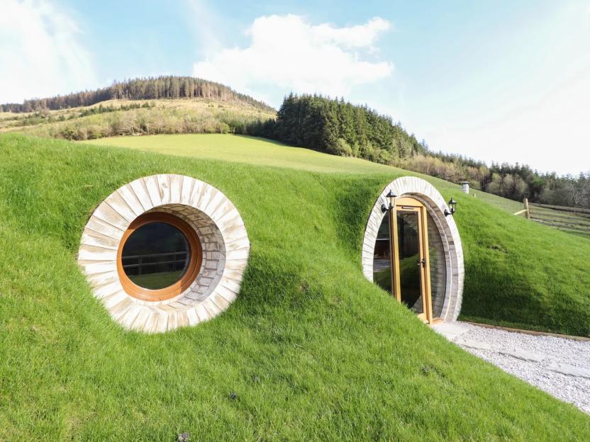 Nant y Garnedd, a Hobbit-like house built into a green hillside with a round window and door.
