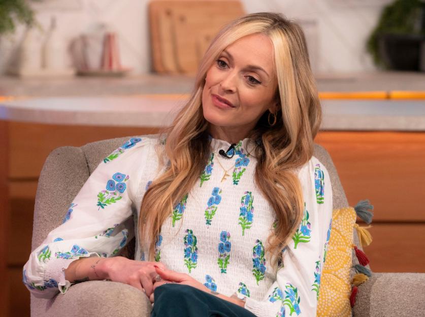 Fearne Cotton sitting in a chair, wearing a white floral blouse.