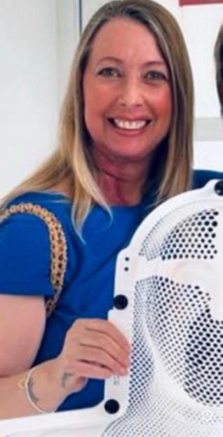Elaine Sawyer, 54, smiling while holding onto a white medical device, after receiving treatment for tongue cancer.