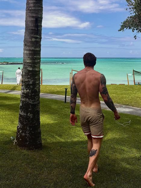 Adam Peaty walking barefoot on grass towards the ocean at One & Only Le Saint Geran Mauritius.