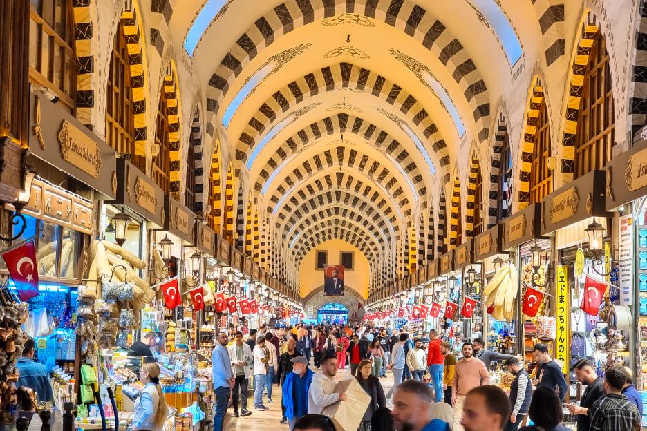 View of the bustling Grand Bazaar in Istanbul with a domed, arched ceiling and many stalls.