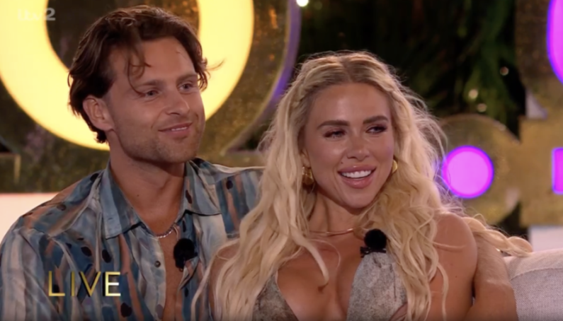 Casey and Gabby smiling during a tense moment in the Love Island final.