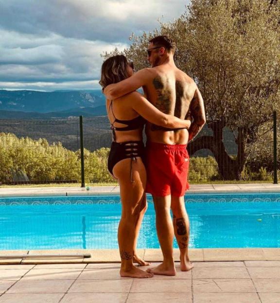 A couple embracing by a swimming pool with mountains in the background.