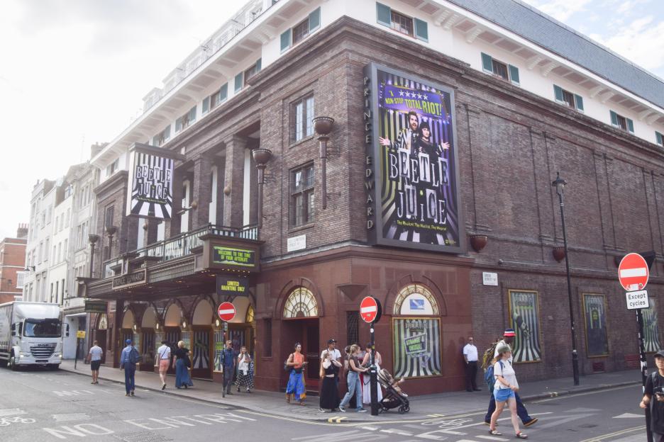 Daytime exterior view of the Prince Edward Theatre in London's Old Compton Street, Soho, showing a "Beetlejuice The Musical" billboard.