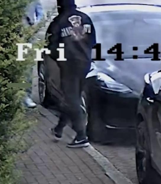 CCTV image of Nandito Badea walking on a sidewalk next to a car.