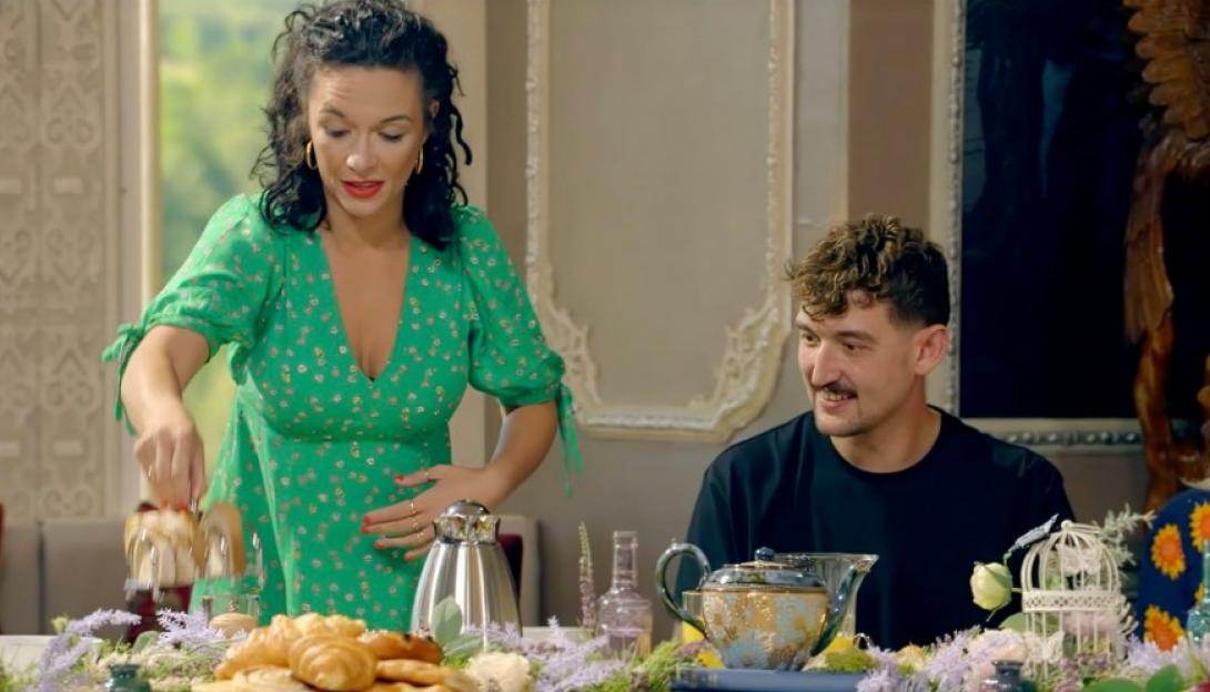 Charlotte Chilton in a green dress and Jonny Holloway in a black shirt sitting at a table with pastries and floral decor.