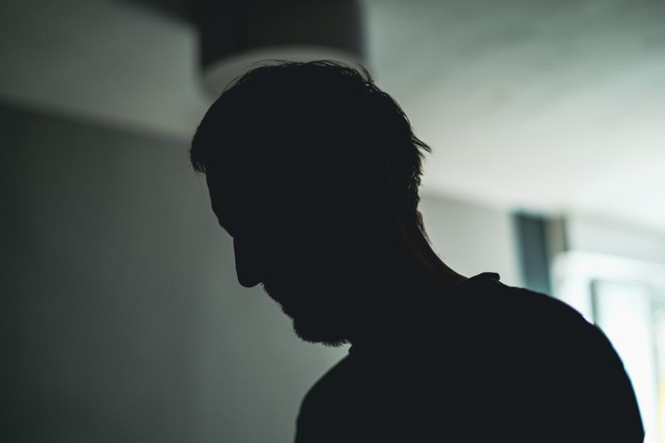 Social alienation concept, silhouette of self-estrangement male in dark room