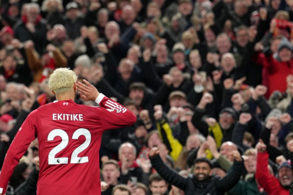 Soccer player Ekitike, wearing a red jersey with number 22, celebrates a goal with the cheering crowd.