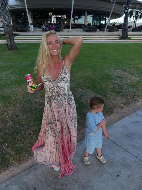 Paris Fury in a pink patterned dress smiles at the camera while holding a drink, with a young boy next to her.