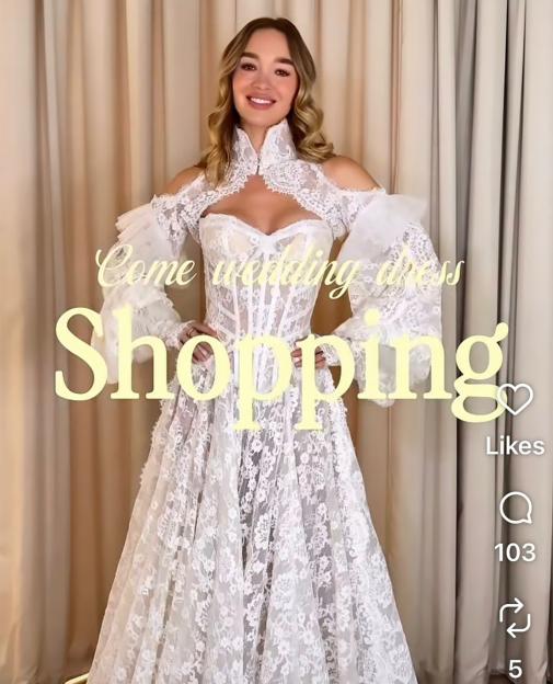 Roxy Horner trying on a lace wedding dress with a high collar and puffed sleeves.