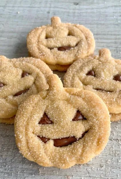 Nutella-stuffed pumpkin cookies covered in sugar, shaped like jack-o'-lanterns.