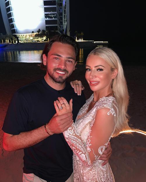 Olivia Attwood and Bradley Dack smiling and holding hands, with the Burj Al Arab in the background.