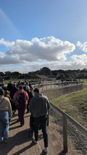 Visitors walking along elevated wooden pathways at Yorkshire Wildlife Park under a partly cloudy sky.