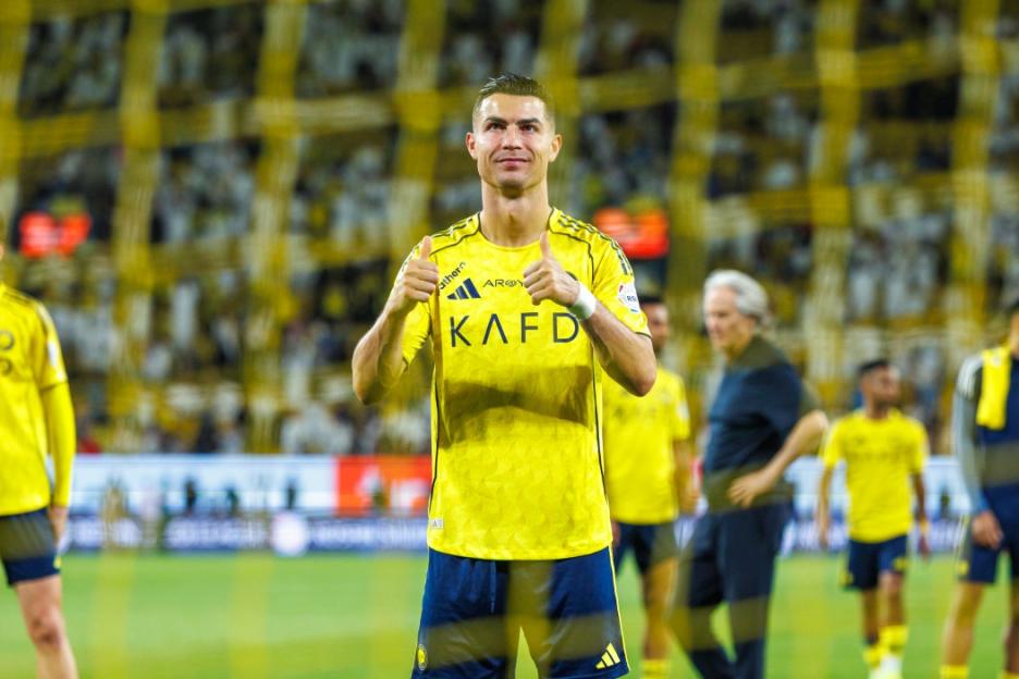 Cristiano Ronaldo in a yellow and blue uniform giving a double thumbs up during the Al Nassr v Al Najmah Saudi Pro League match.